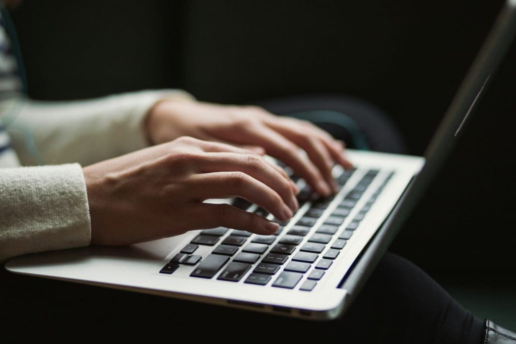 Zwei Hände tippen auf der Tastatur eines Laptops