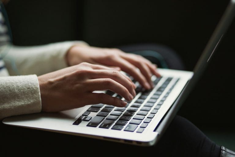 Zwei Hände tippen auf der Tastatur eines Laptops