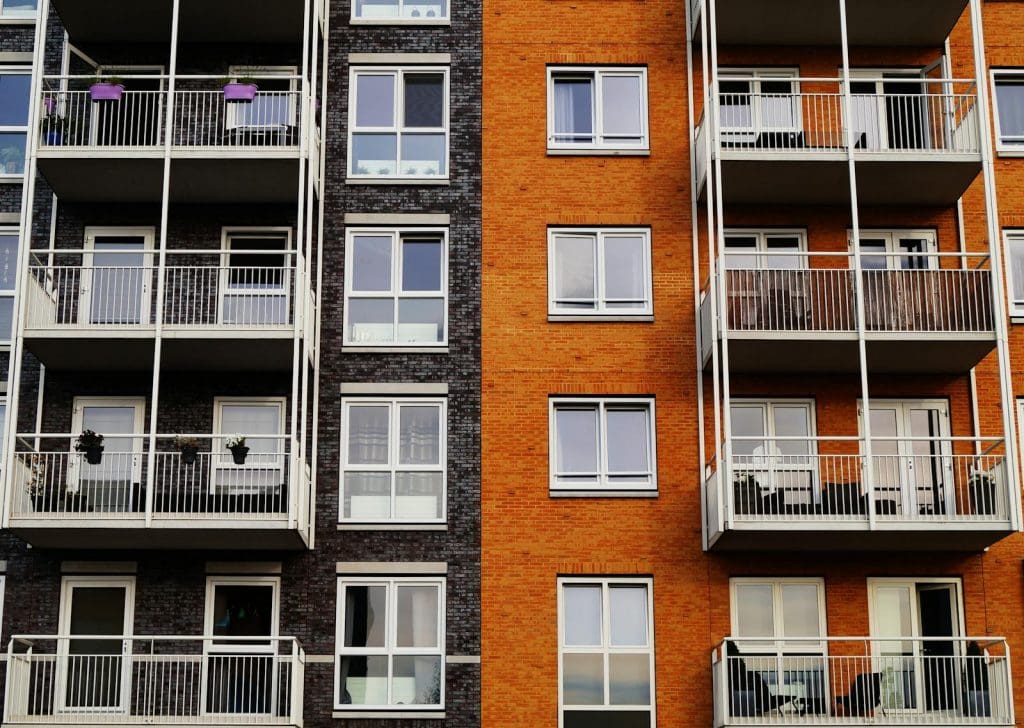 Detailansicht der Außenfassade eines modernen Wohnhauses mit Balkonen und Glasfenstern.
