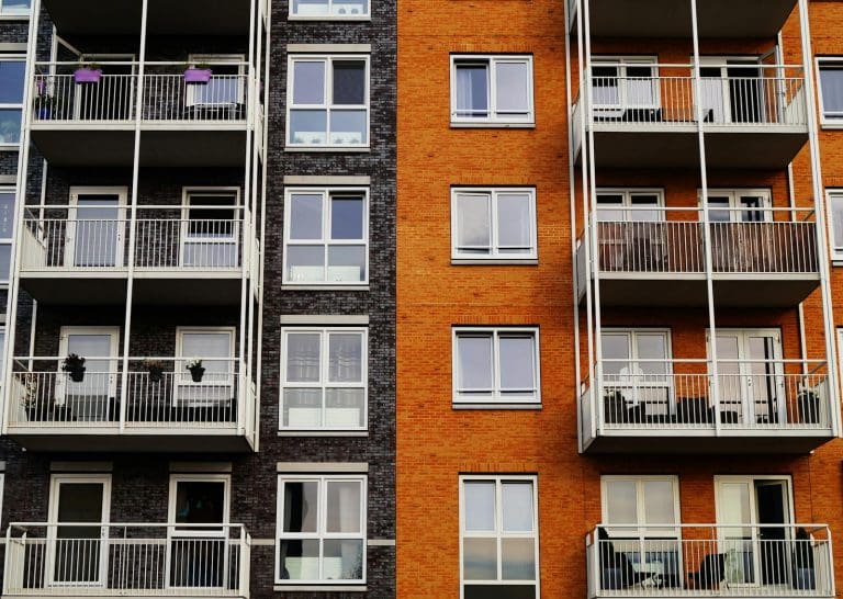 Detailansicht der Außenfassade eines modernen Wohnhauses mit Balkonen und Glasfenstern.