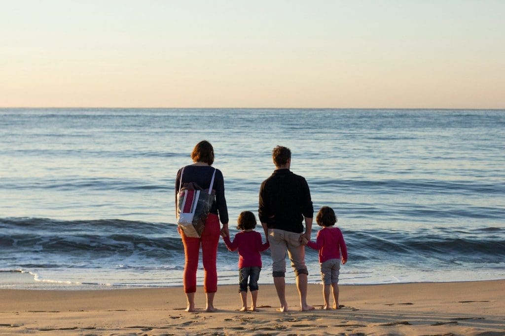 familie mit vier Personen, die am Strand stehen