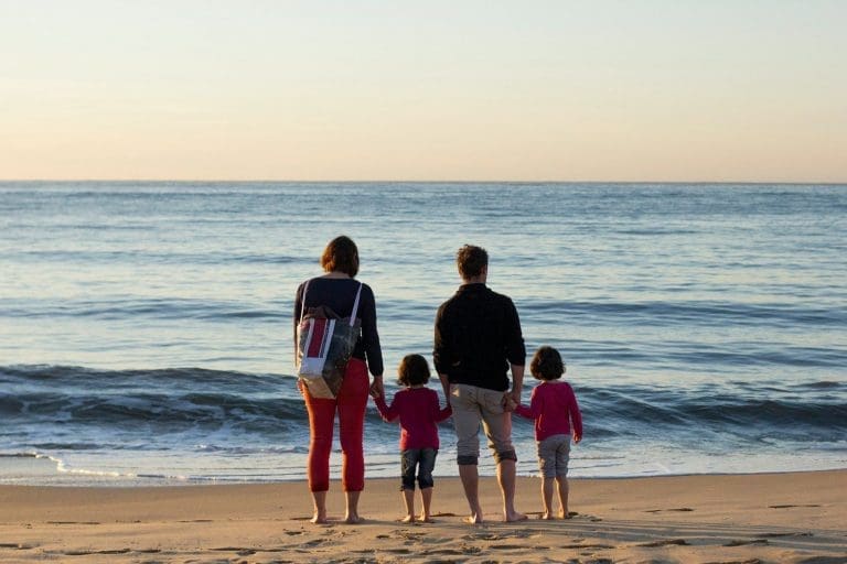 familie mit vier Personen, die am Strand stehen