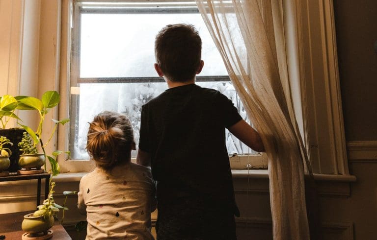 Ein Junge und ein Mädchen stehen am Fenster und schauen nach draußen.